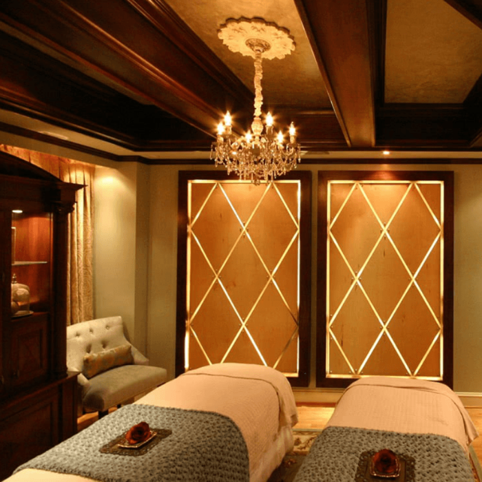 Luxurious spa room with two massage tables, a chandelier, and decorative elements.