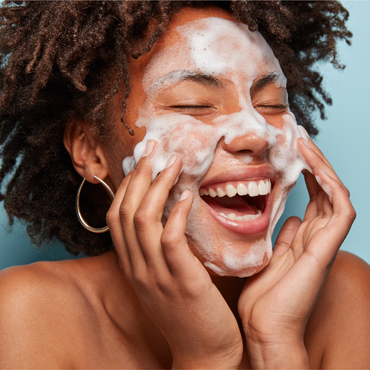 Woman applying a facial mask with a blue background